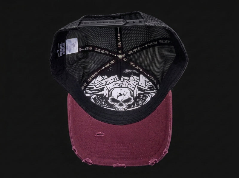 A distressed snapback cap shown from the back, featuring a black mesh back with a white graphic of a skull and roses, and a faded burgundy fabric brim.