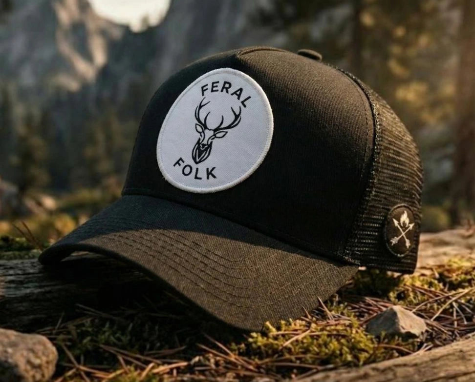 Black and brown cap with 'Feral Folk' logo on a natural background