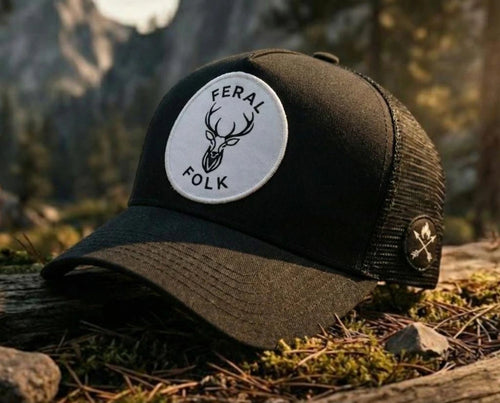 Black and brown cap with 'Feral Folk' logo on a natural background