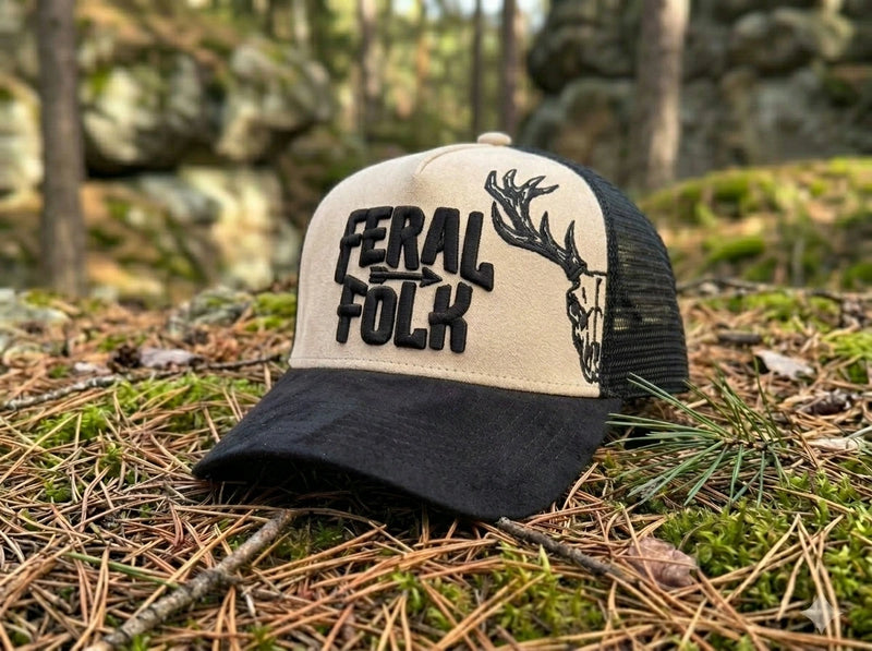 Trucker hat with 'Feral Folk' text and deer design on a forest floor background